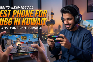 ​A digital poster with the text "KUWAIT’S ULTIMATE GUIDE: BEST PHONE FOR PUBG IN KUWAIT" in bold orange letters, featuring a smiling man in a Thobe playing a game on a smartphone. Below the main text are technical details: "ULTRA FPS | 90HZ | TOP PERFORMANCE." The foreground shows close-up hands holding a smartphone with the PUBG Mobile game in action. In the background is a window view of the lit Kuwait Towers at night.